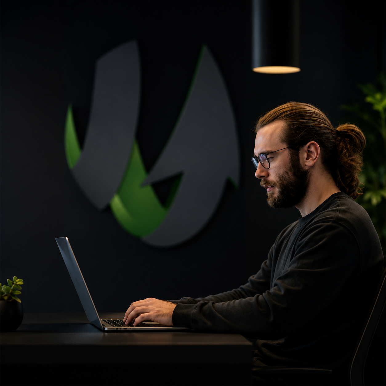 Designer working on SharpSpring at a desk lit by the SharpSpring wall mark